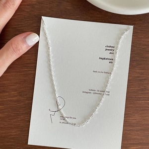 Close-up of a minimalist S925 sterling silver fine chain necklace on textured card