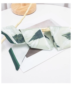 Detailed view of green floral silk scarf ribbon draped over a natural wooden branch