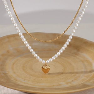 Double-layered gold chain necklace with white pearl strand and heart pendant charm