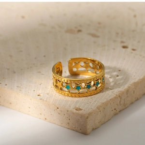 Close-up of 18K gold plated star ring with blue enamel inlay on a beige stone surface