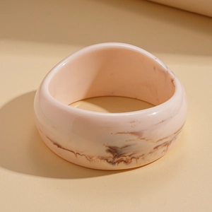 Macro shot of minimalist thick resin bangle with brown marble texture on beige surface