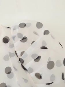 Close-up of semi-transparent organza fabric with elegant black polka dots and mesh texture