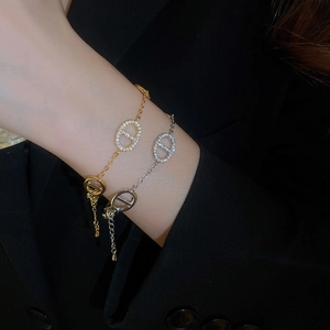 Detail view of interlocking gold and silver zircon bracelets on black suit fabric