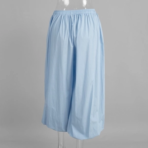Detail of light blue wide-leg harem pants with elastic high waist and breathable fabric