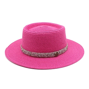 Detailed texture of rose red boater straw hat with rhinestone band and gold M badge