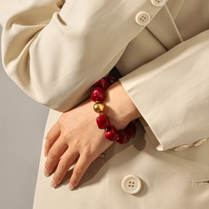 Retro beaded bracelet with red marble texture stones and large gold bead accent on wrist