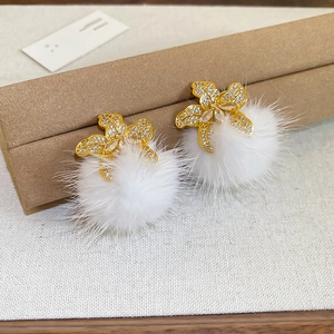 Detail of flower stud earring with sparkling rhinestones and soft white faux fur pompom