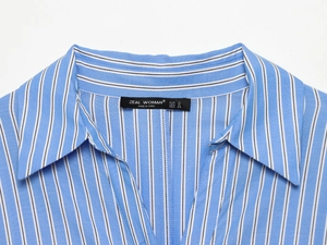 Detail eines blau-weiß gestreiften Hemdkleids mit schwarzem Satin-Markenetikett