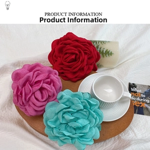 Detail of three fabric rose hair claws in red, pink, and green on a wooden tray
