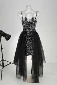 Detail of black sequined mini dress featuring crystal straps and a detachable tulle train