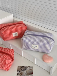 Detalle de bolsas de cosméticos acolchadas a cuadros en color rojo y púrpura