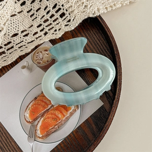 Detail of teal gradient oval hair claw clip with gold France Handmade lettering on wood