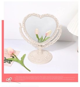 Detail of heart-shaped vintage vanity mirror with floral embossed frame and round base