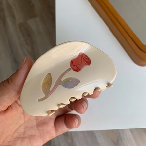 Elegant beige shark clip with a detailed red relief rose and iridescent leaf accents