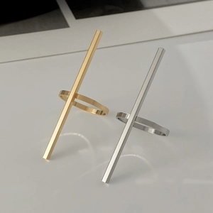 Dettaglio di anelli geometrici a barra lunga in finiture oro e argento lucido