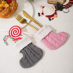 Pink and grey knitted Christmas stocking cutlery holders on a festive dinner table setting