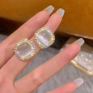 Close-up of square cat eye stone earrings with micro-set crystals and gold plating