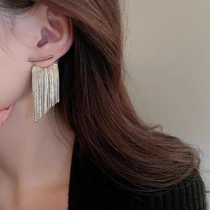 Close-up of a silver long chain tassel earring on a model with metallic curved top