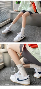 Detail of white cotton crew socks with Suxinaim text paired with retro leather sneakers