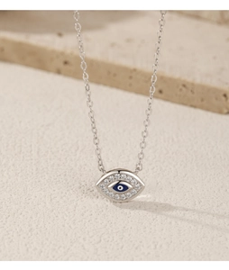 Macro shot of silver paperclip chain necklace featuring a blue evil eye stone pendant