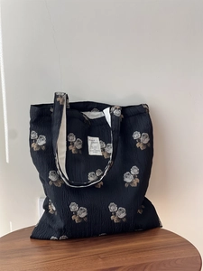 Macro detail of black textured fabric shoulder bag with gray rose floral patterns