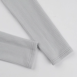 Detail shot of light gray ribbed knit fabric on a long sleeve bodysuit with neat stitching