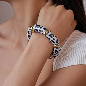 Detail of leopard print acrylic segment bracelet with golden metal spacers on wrist