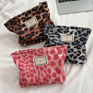 Dettaglio di pochette trucco in tela leopardata con cerniere in metallo ed etichette