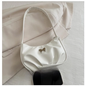 Detail of white pleated crescent bag with silver butterfly charm and soft PU texture