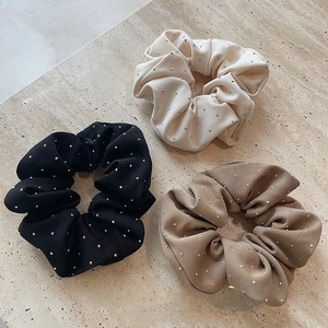 Close-up of three premium solid-color scrunchies with fine silver rhinestones on stone base
