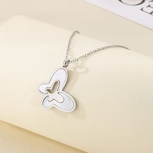 Detailed view of silver butterfly pendant with white shell inlay on a jewelry stand