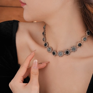 Detail of vintage flower necklace with dark stones on gold-plated chain worn by a model
