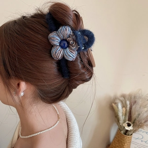 Détail de la pince à cheveux en peluche bleu marine avec fleur tissée et perle sur modèle