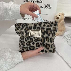Detail of leopard print plush cosmetic bag showing hand placing cream inside