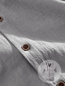 Close-up of linen fabric texture and vintage brown buttons on a grey hooded shirt