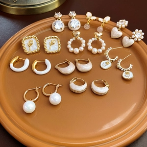 Flat lay of gold and pearl earrings set with rose, heart, and hoop designs in a tray