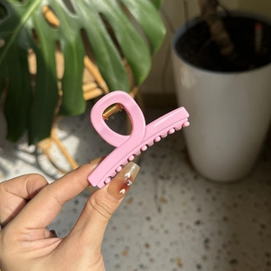 Detailed close-up of a sturdy pink plastic hair claw clip with high-quality metal spring
