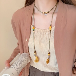 Detail of bohemian wooden bead waist chain and necklace with tassel and silver pendant