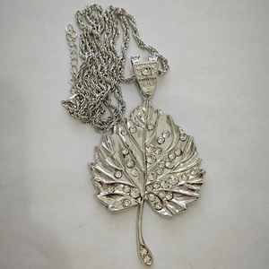 Detailed view of large silver maple leaf pendant with rhinestones on twisted chain