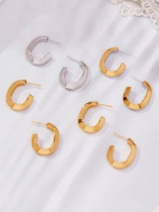 Macro view of C-shaped grooved hoop earrings in 18k gold and silver finishes