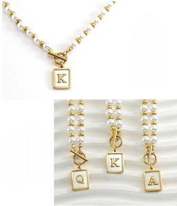 Detail of OT buckle pearl necklace with 18K gold plated stainless steel initial pendants