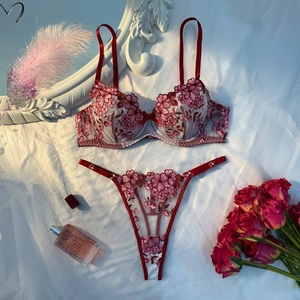 Flat lay of sheer floral embroidery lingerie set in deep red and pink with roses
