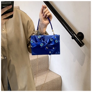 Detail of blue velvet evening clutch with a large rhinestone bow and metallic chain strap
