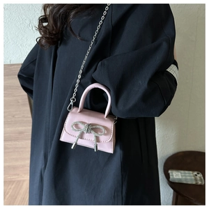 Detail of pink matte mini bag with silver rhinestone bow and metallic chain strap