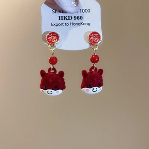 Detail of red flocked animal earrings with Fu character studs and golden tassel accents
