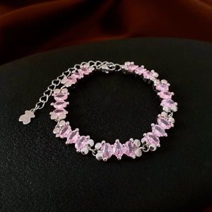 Detail of silver bracelet featuring pink oval gemstone and cute bear-shaped metal charm