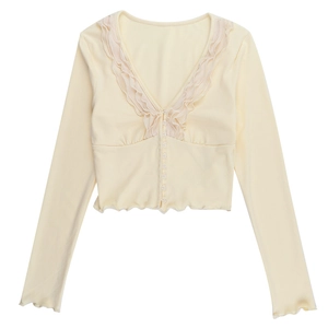 Detail of light yellow knit top featuring deep V-neck with ruffles and lettuce edge hem