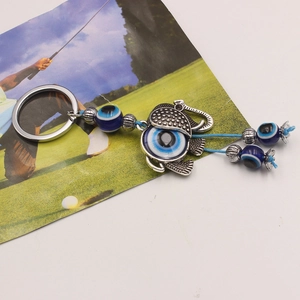 Detailed close-up of a silver elephant keychain with blue evil eye beads and woven rope