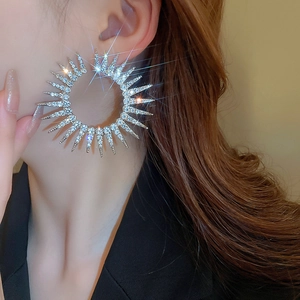 Macro detail of silver sunburst earrings with sparkling diamonds on a model's ear