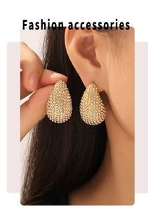 Detailed close-up of water drop stud earrings with gold plating and paved crystals